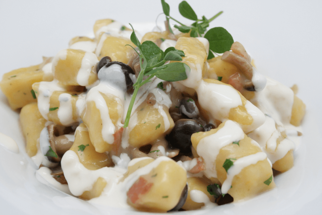 Piatto di gnocchi alla zucca con funghi Pioppini, fonduta di Taleggio e pancetta